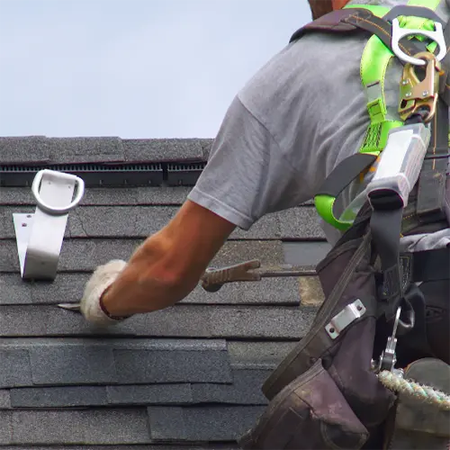 Roofer with safety harness working on roof maintenance.